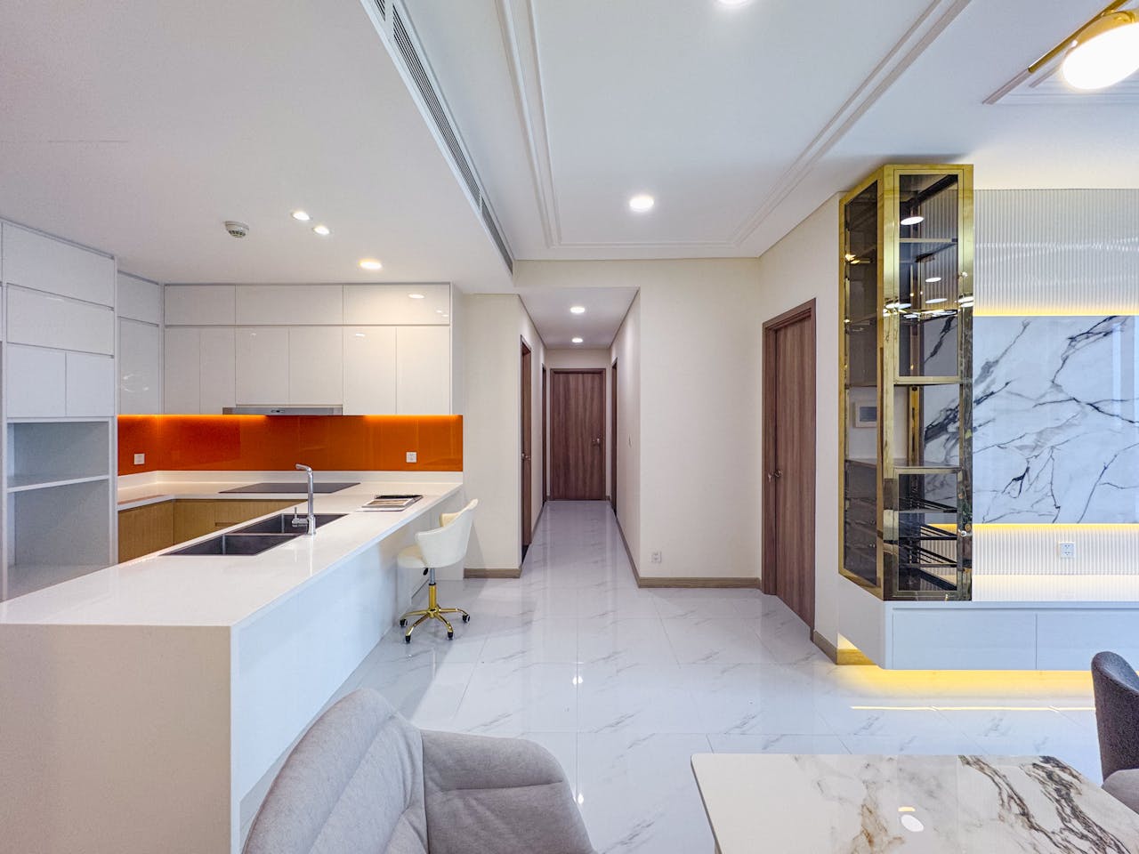 who-we-are Contemporary open-plan kitchen and living space with marble decor and orange accents.