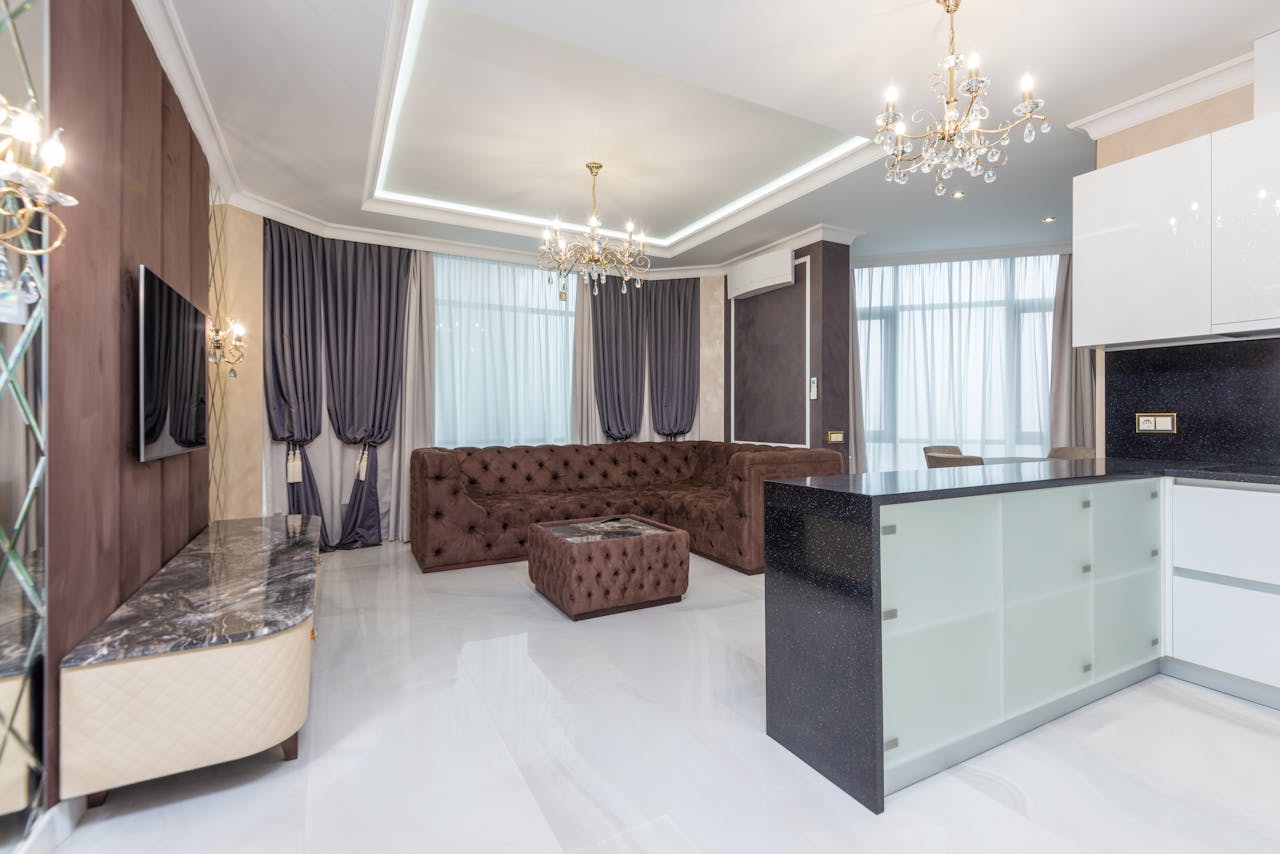 our-story Spacious modern living room featuring elegant chandeliers, plush sofa, and contemporary decor.